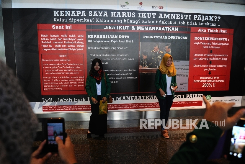 Mahasiswa berfoto sekuritas dengan latar belakang sosialisasi Tax Amnesty saat digelar pameran sekuritas di Bursa Efek Indonesia (BEI), Jakarta, Kamis (21/7).