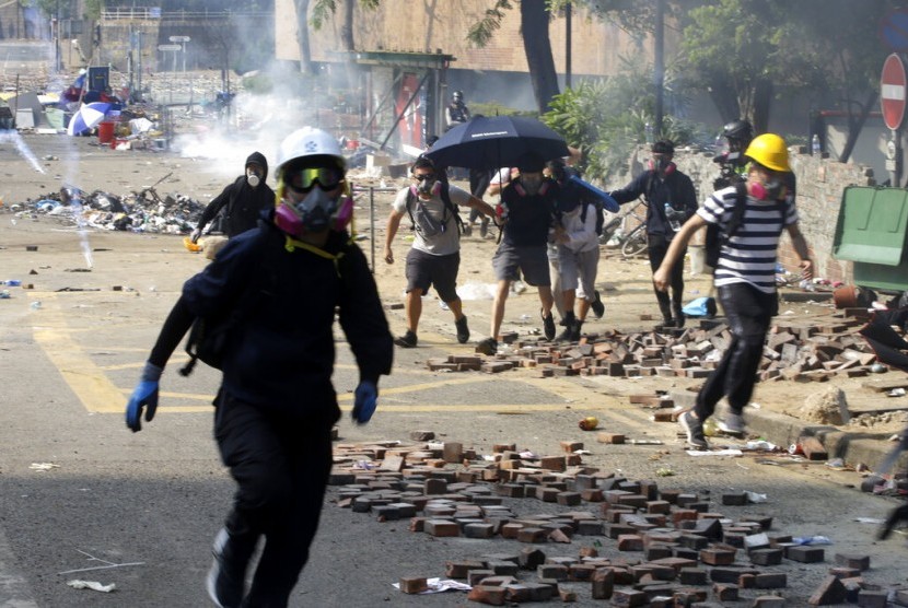 Mahasiswa demonstran berlarian saat polisi menembakkan gas air mata di kampus Hong Kong Polytechnic University di Hong Kong, Senin (18/11). 
