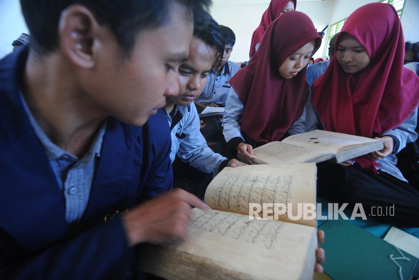 Mahasiswa IAIN Jember mengamati kitab kuno saat Ngaji Manuskrip di Padepokan Raden Umro, Ponpes Sumber Anyar, Pamekasan, Jawa Timur, Ahad (21/4/2019).(Antara/Saiful Bahri)