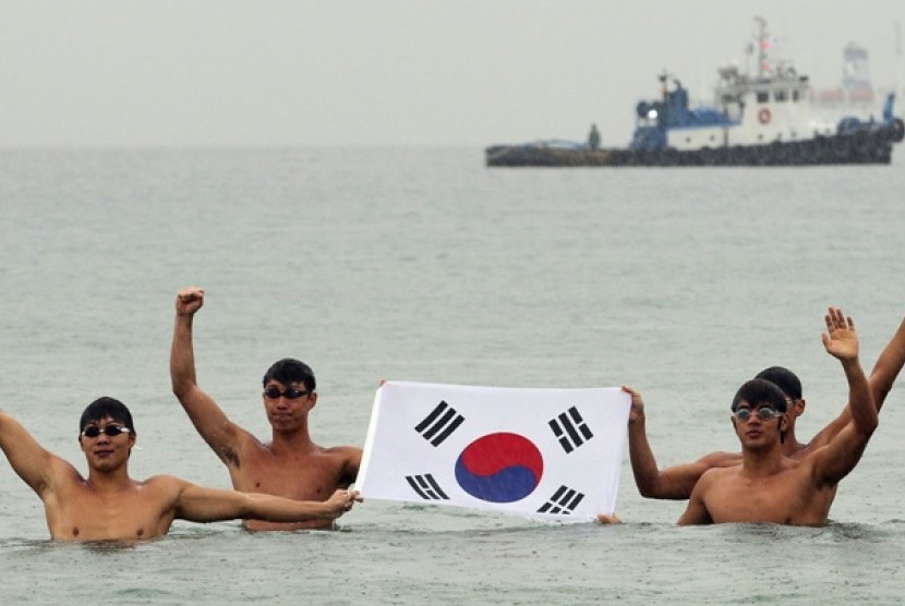 Mahasiswa Korea Selatan mengibarkan bendera Korea Selatan di  pelabuhan timur Ujin, Korea Selatan sebelum melakukan renang estafet ke Kepulauan Dokdo yang menjadi sengketa antara Korea Selatan dan Jepang. 