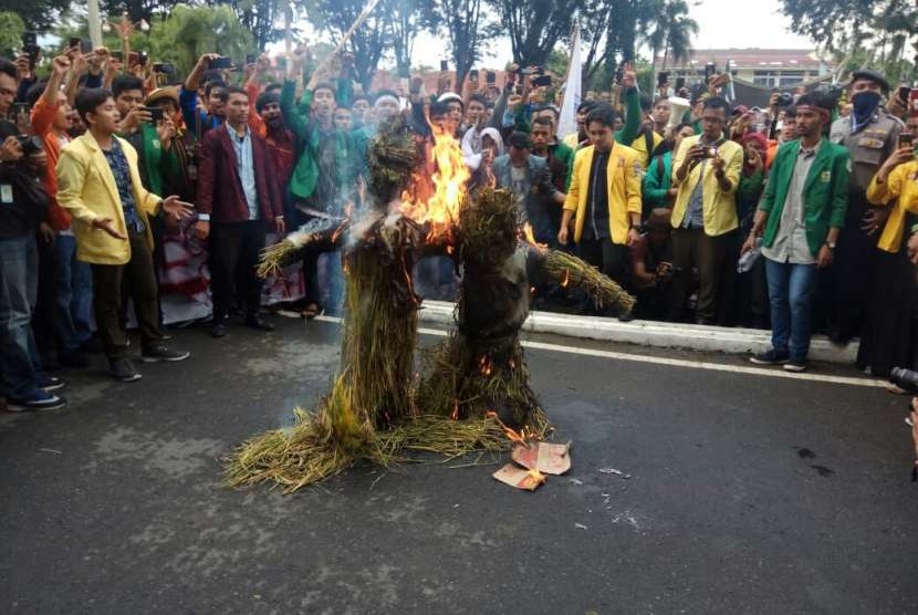 Mahasiswa melakukan demonstrasi dengan membakar boneka jerami yang ditempel foto Mendag dan Dirut Bulog, Senin (24/9). Aksi ini sebagai bentuk protes atas kisruhnya kebijakan soal impor beras saat ini. 
