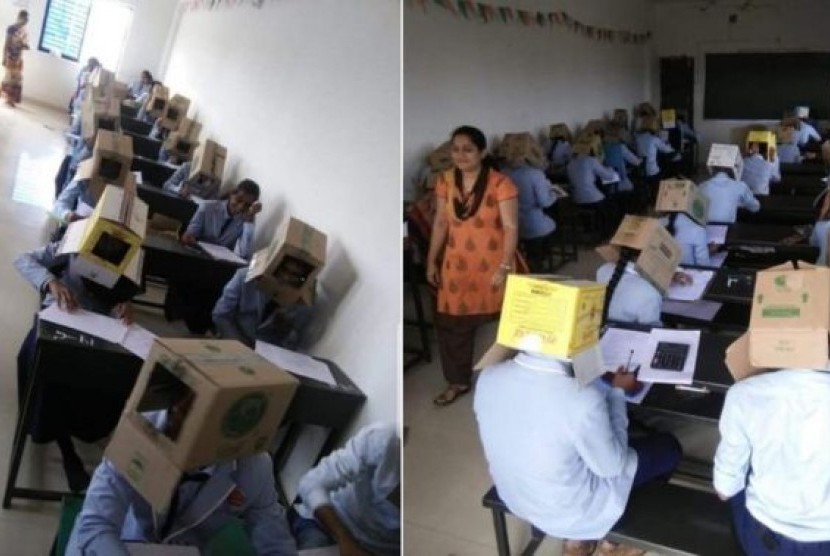 Mahasiswa menggunakan kardus di kepala selama ujian kimia di Bhagat Pre-University College di Haveri, negara bagian Karnataka, India agar tidak menyontek.