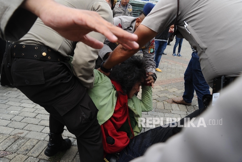  Mahasiswa tergabung dalam Gerakan Bersama Lawan Industri Rokok (Gebrak) diamankan petugas saat melakukan aksi penolakan World Tobacco Process And Machinery (WTPM) di Jiexpo, Jakarta, Rabu (27/4). (Republika/Tahta Aidilla)