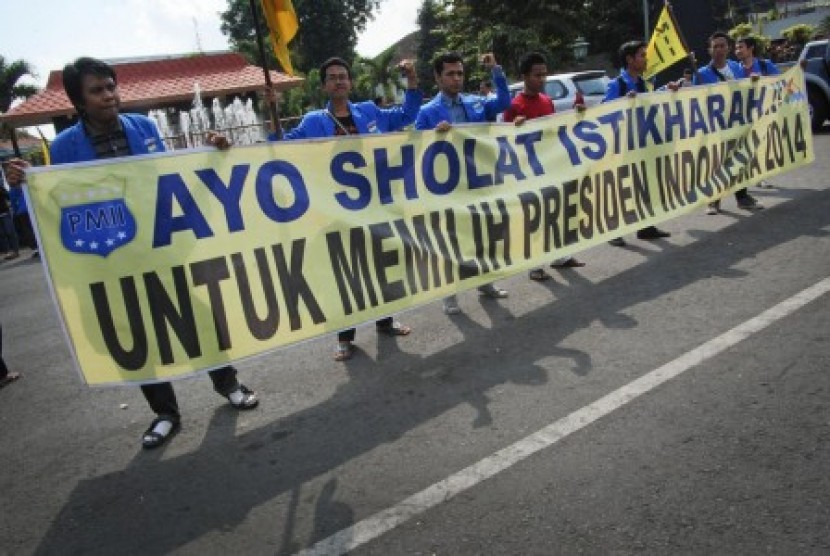 Mahasiswa yang tergabung dalam Pergerakan Mahasiswa Islam Indonesia (PMII) Kabupaten Kudus membentangkan poster yang menghimbau melakukan shalat istikarah untuk memilih Presiden Indonesia 2014 di Alun-alun Kudus, Jateng, Senin (9/6). 