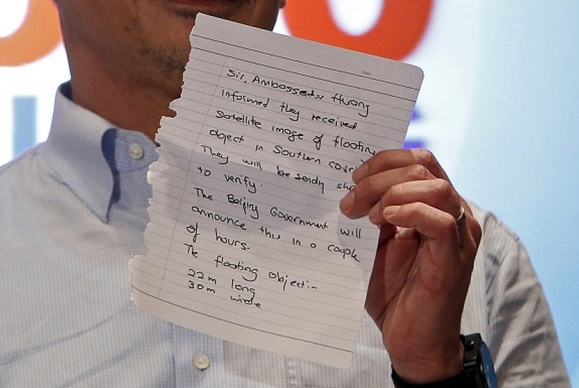 Malaysia's acting Transport Minister Hishammuddin Hussein holds up a note that he has just received on a new lead in the search for the missing Malaysia Airlines Flight MH370, during a news conference at Kuala Lumpur International Airport March 22, 2014.