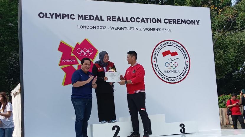 Mantan lifter putri Indonesia, Citra Febrianti menerima medali perak Olimpiade 2021 London setelah penantiannya selama 10 tahun. Anggota Komite Olimpiade Internasional (IOC) yang juga Menteri BUMN, Erick Thohir (kiri) mengalungkan medali pereka itu bertempat di Plaza Timur, Kompleks Gelora Bung Karno, Senayan, Jakarta, Ahad (18/9/2022). 