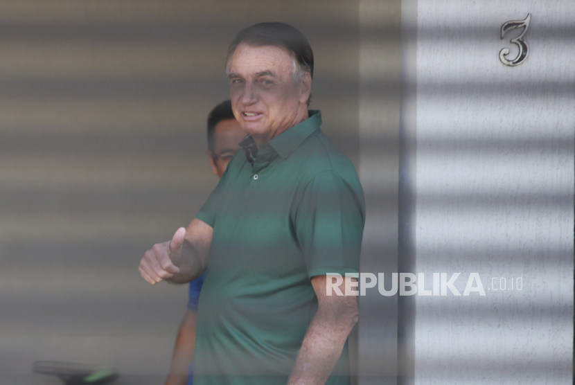 Mantan Presiden Brasil Jair Bolsonaro mengacungkan jempol sambil berdiri di pintu masuk rumahnya tempat ia menjalani tahanan rumah di Brasilia, Brasil, Kamis, 11 September 2025.