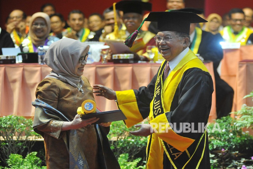 Mantan Wakil Presiden Jusuf Kalla (kanan) menyerahkan sertifikat kepada istrinya, Mufidah Jusuf Kalla (kiri), saat penganugerahan gelar doktor kehormatan (Dr. HC) di Universitas Negeri Padang (UNP) Padang, Sumatera Barat, Kamis (5/12/2019).