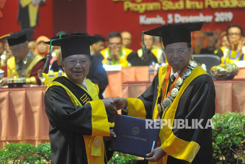 Mantan Wakil Presiden Jusuf Kalla (kiri) berjabat tangan dengan Rektor Universitas Negeri Padang (UNP) Ganefri (kanan) saat penganugerahan gelar doktor kehormatan (Dr. Honoris Causa), di kampus tersebut di Padang, Sumatera Barat, Kamis (5/12/2019).