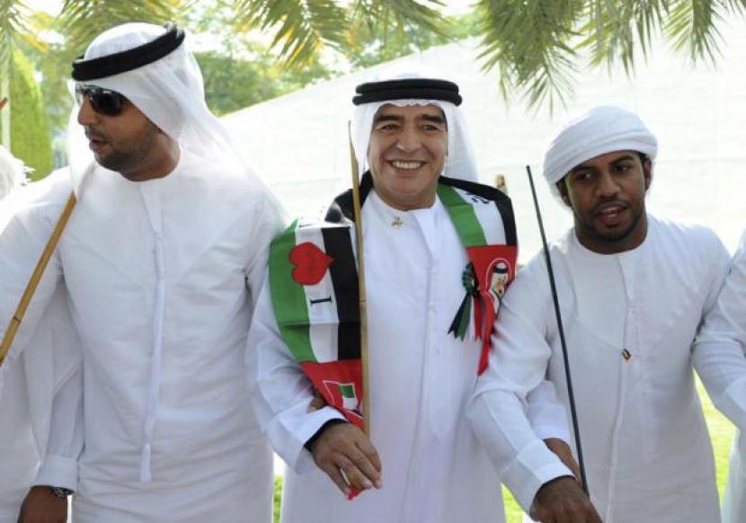 Maradona mengenakan pakain khas Arabia dan mengenakan syal bendera Palestina.