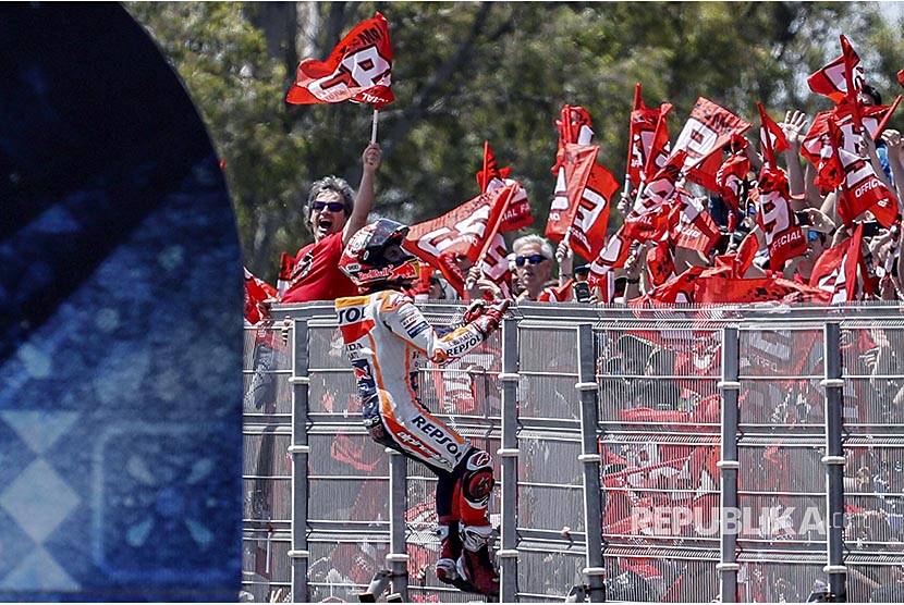 Marc Marquez dari tim Repsol Honda memanjat pagar merayakan kemenangannya bersama penonton pada balapan MotoGP Spanyol di Sirkuit Jerez, Spanyol, Ahad (6/5)