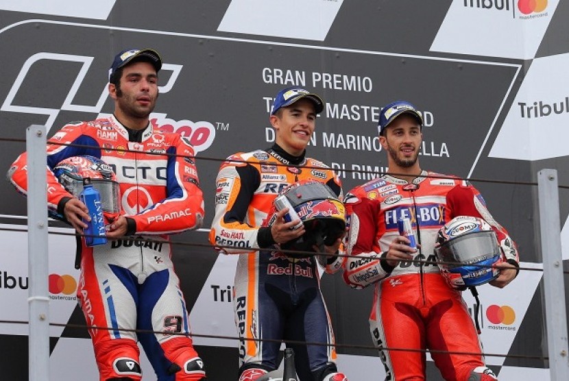 Marc Marquez (tengah) diapit dua pembalap Italia, Danilo Petrucci (kiri) dan Andrea Dovizioso pada podium juara MotoGP San Marino, Ahad (10/9).
