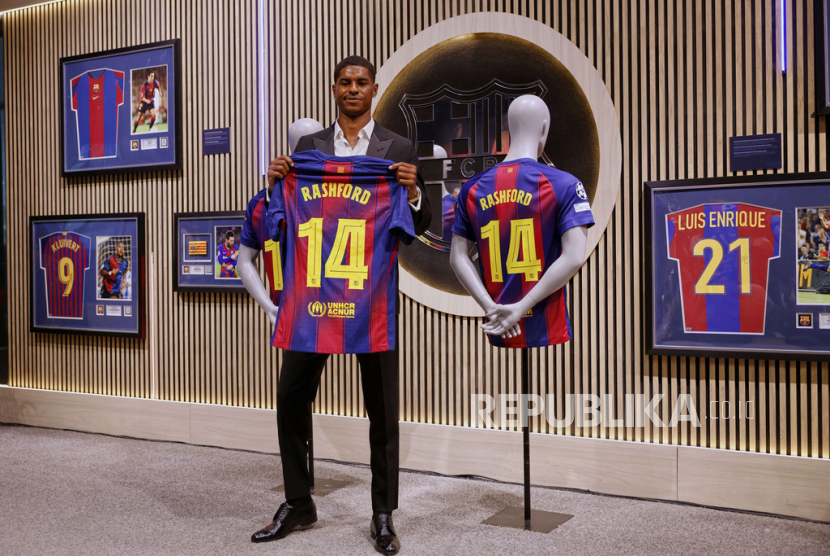 Marcus Rashford memegang kostum nomor 14 yang akan dikenakannya di Barcelona pada musim depan.