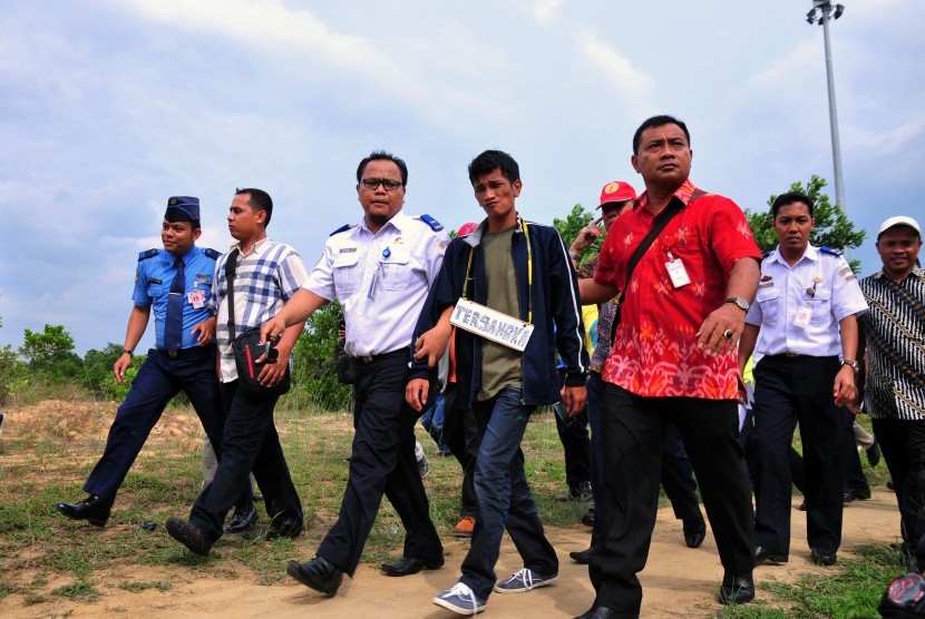 Mario Steven Ambarita (tengah) dikawal oleh personel Polda Riau dan Penyidik PPNS Kementerian Perhubungan menjalani rekonstruksi kasus penyusupan ke pesawat di Bandara Sultan Syarif Kasim II, Kota Pekanbaru, Riau, Jumat (10/4).