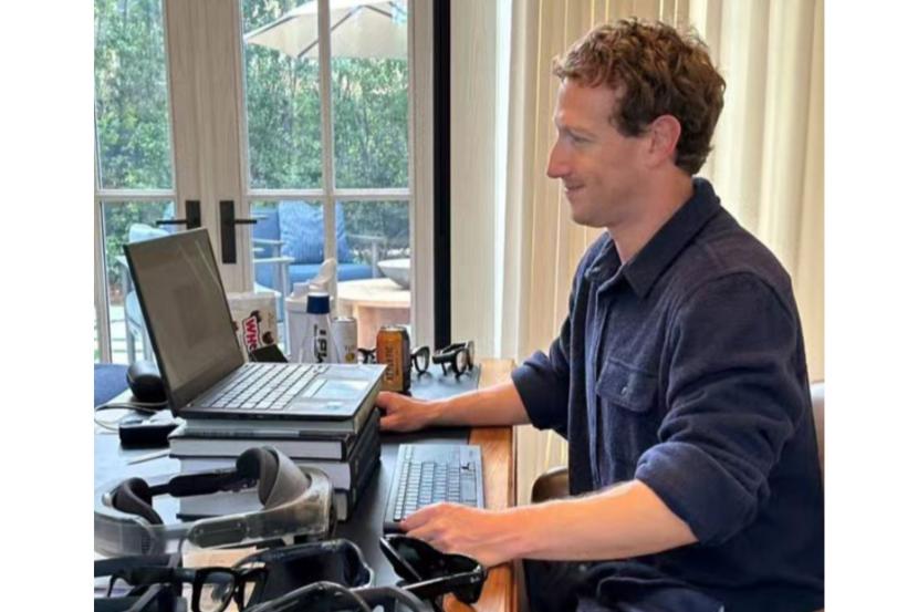 Mark Zuckerberg membagikan fotonya bekerja dengan laptop di atas tumpukan bukj.
