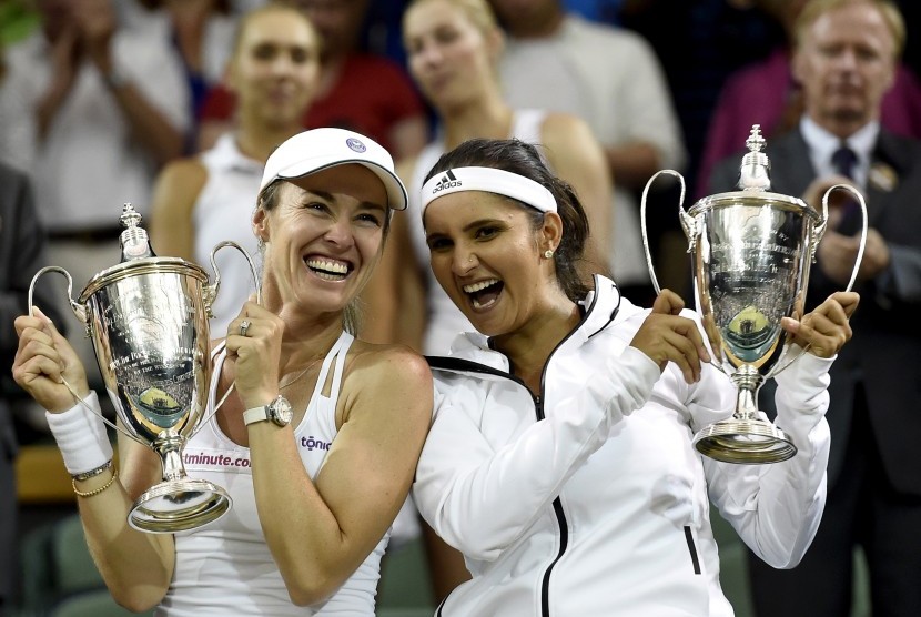 Martina Hingis (L) of Switzerland and Sania Mirza of India celebrate with their trophies after winning against Ekaterina Makarova and Elena Vesnina of Russia during their Women's doubles final match for the Wimbledon Championships at the All England Lawn T