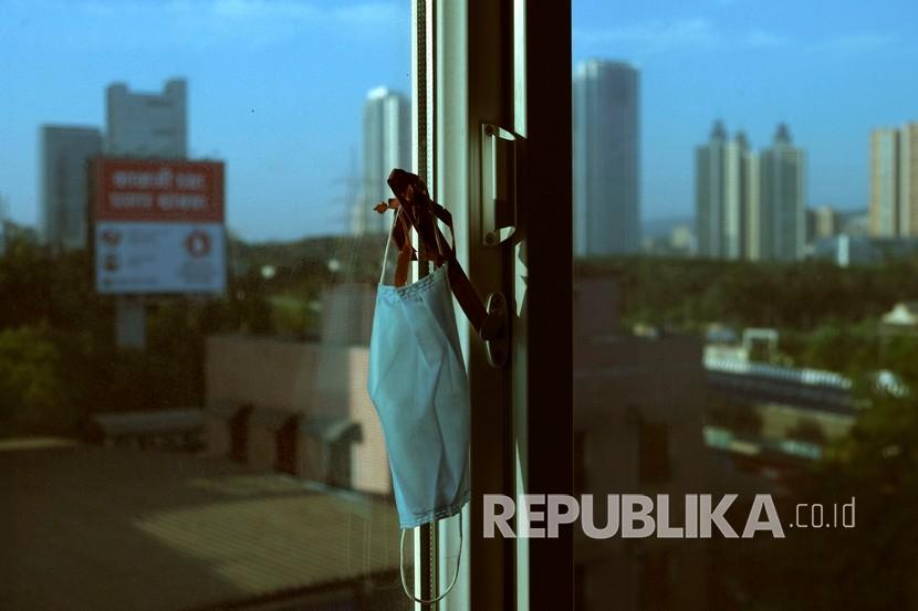 Masker fotografer Associated Press Rafiq Maqbool tergantung dengan aksesoris pesona keberuntungan yang dibuat oleh putrinya , di sebuah kamar hotel tempat ia dikarantina di Mumbai, India, Kamis (23/4).  
