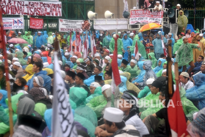 Mass of 212 rally phase II stayed in front of the gate of Parliamentary building, Jakarta, even though the rain was pouring, Tuesday (Feb 21)