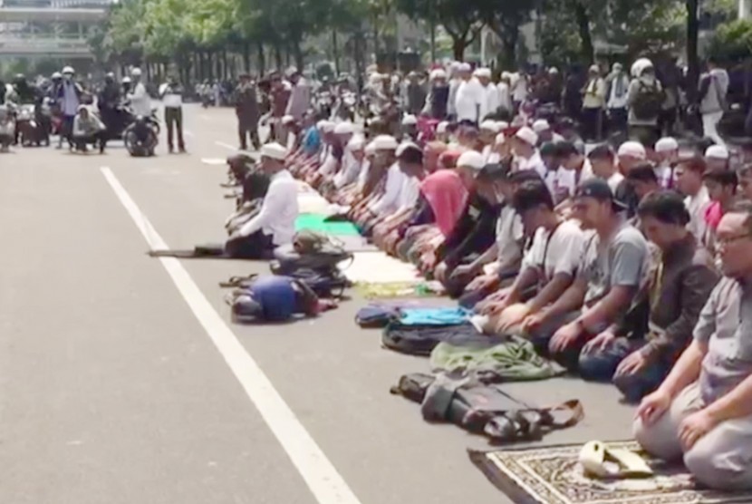 Massa aksi damai melakukan shalat berjamaah di Jalan MH Thamrin, Jakarta Pusat, Rabu (22/5).