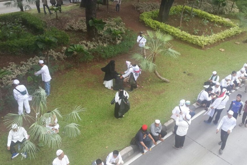 Massa Aksi Damai membersihkan sampah yang tertinggal di taman di sisi jalan Medan Merdeka Barat, Jumat (4/11).