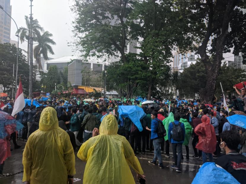 Massa aksi menolak RUU Cipta Kerja di kawasan Monas, Jakarta Pusat membubarkan diri setelah hujan deras turun. Jumat (16/10).