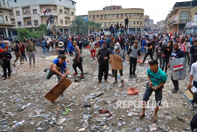 Massa anti pemerintah melemparkan batu ke arah petugas keamanan dalam unjukrasa di Baghdad, Irak, Kamis (28/11).