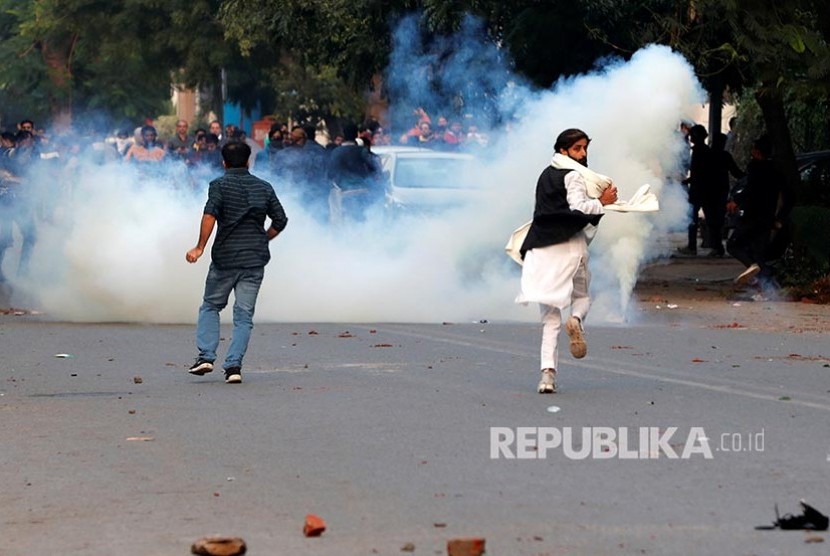 Massa berunjukrasa penentang Revisi UU Kewarganegaraan baru melarikan diri dari tembakan gas air mata polisi India di New Delhi, India, Ahad (15/12). Saat ini India sedang dilanda aksi demonstrasi memprotes UU kewarganegaraan.