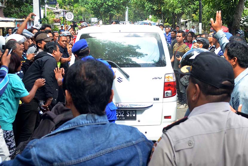 Massa berusaha menyerang mobil yang membawa tersangka Agustinus usai menjalani proses pra-rekonstruksi pembunuhan Angeline di Jalan Sedap Malam, Kota Denpasar, Bali, Kamis (11/6). 