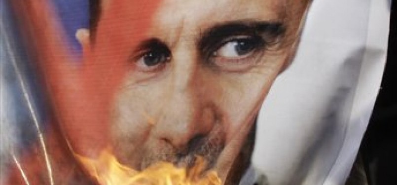 Massa demonstran membakar foto Presiden Suriah, Bashar Assad, di depan kantor pusat Liga Arab, Kairo, Sabtu (12/11)