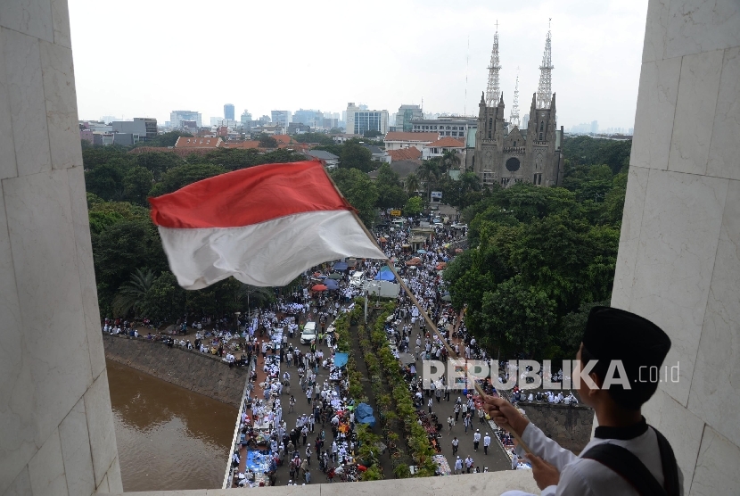  Massa GNPF mengibarkan bendera Indonesia sebelum melaksanakan sholat jumat berjamaah di Masjid Istiqlal, Jakarta, Jumat (5/5). 