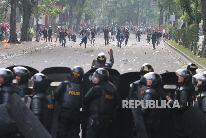 Massa melemparkan batu ke arah barisan polisi saat unjuk rasa menolak UU KPK hasil revisi dan RUU KUHP, di kawasan Titik Nol Kota Medan, Sumatera Utara, Jumat (27/9/2019).