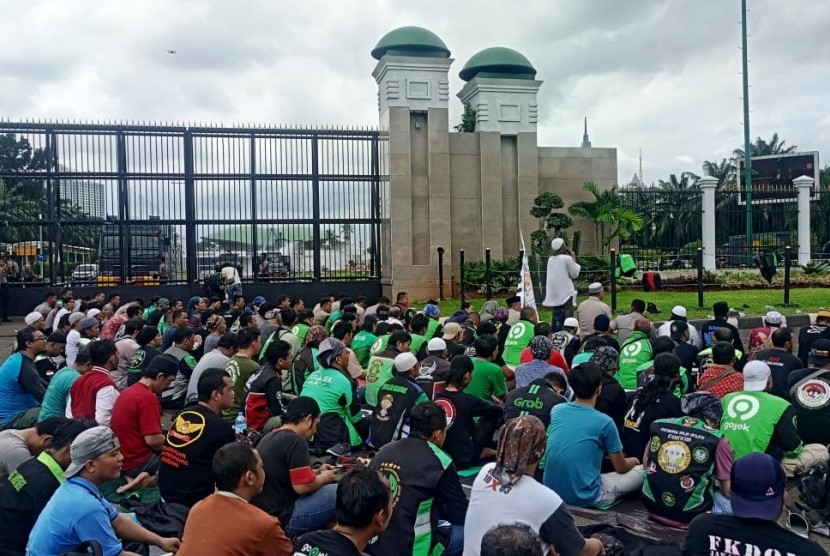 Massa Ojek Daring menggelar salat Jumat berjamaah di depan Gerbang Kompleks Parlemen RI, Jalan Gatot Subroto, Jakarta, Jumat (28/2). 