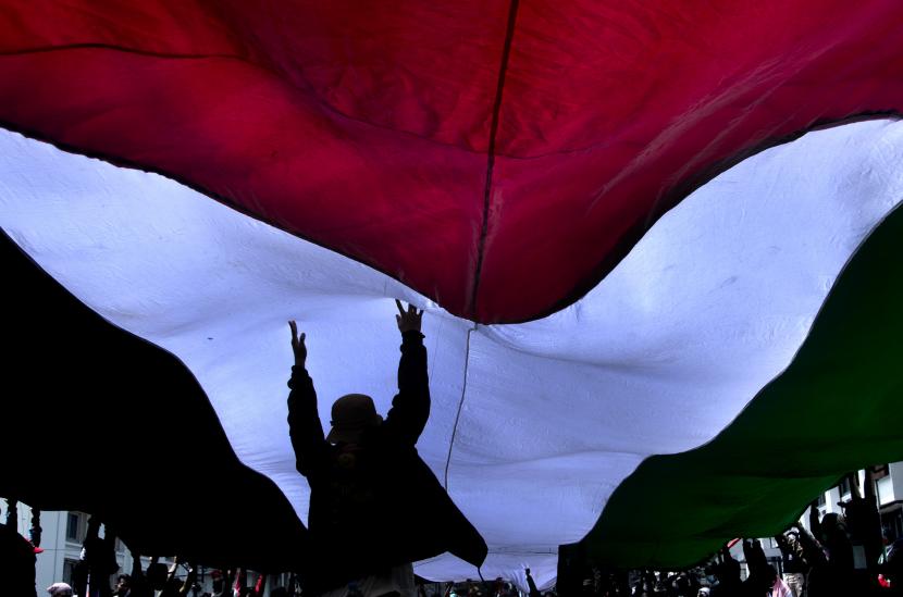 Massa yang tergabung dalam Aliansi Rakyat Jawa Barat Peduli Palestina membentangkan bendera Negara Palestina saat aksi pawai dukung Palestina di Bandung, Jawa Barat.
