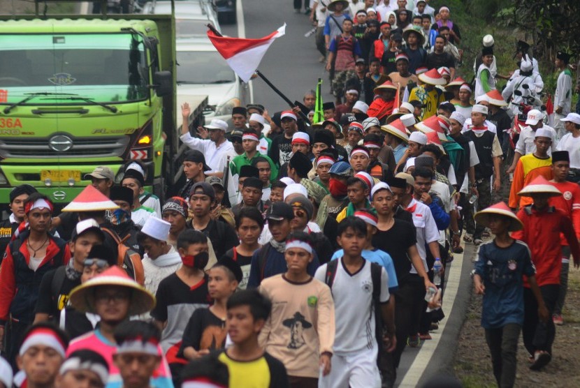 Massa yang tergabung dalam Gerakan Nasional Pengawal Fatwa Majelis Ulama Indonesia (GNPF-MUI) berjalan kaki menuju Jakarta di Jalan Raya Tasikmalaya-Malangbong, Kampung Cipeudeuy, Kabupaten Garut, Jawa Barat, Selasa (29/11). 