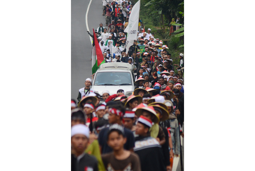 Massa yang tergabung dalam Gerakan Nasional Pengawal Fatwa Majelis Ulama Indonesia (GNPF-MUI) berjalan kaki menuju Jakarta di Jalan Raya Tasikmalaya-Malangbong, Kampung Cipeudeuy, Kabupaten Garut, Jawa Barat, Selasa (29/11).