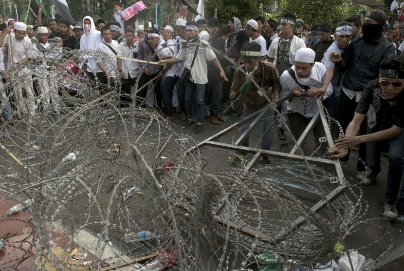 Massa merusak kawat berduri saat unjuk rasa 4 November di Jakarta, Jumat (4/11).