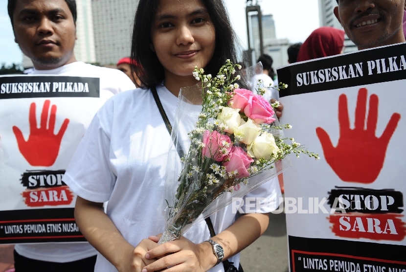 Massa yang tergabung dalam Lintas Pemuda Etnis Nusantara membawa poster saat aksi kampanye di Bundaran HI, Jakarta, Ahad (9/10).