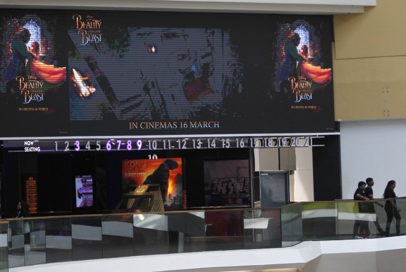 Masyarakat berjalan di bawah layar besar yang menunjukkan iklan film Beauty and the Beast di Kuala Lumpur, Malaysia.