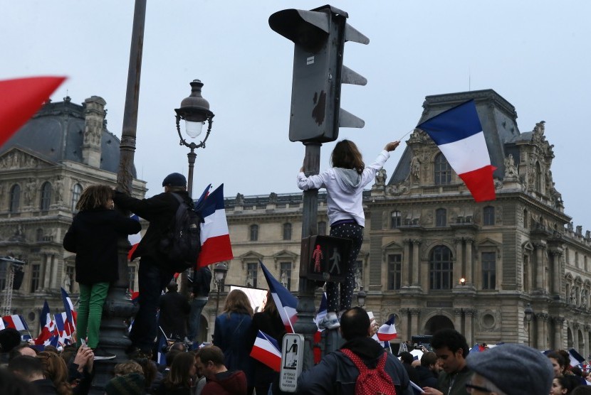 Masyarakat mengibarkan bendera Prancis di kawasan Museum Louvre tempat Emmanuel Macron merayakan kemenangannya dalam pemilu Prancis.