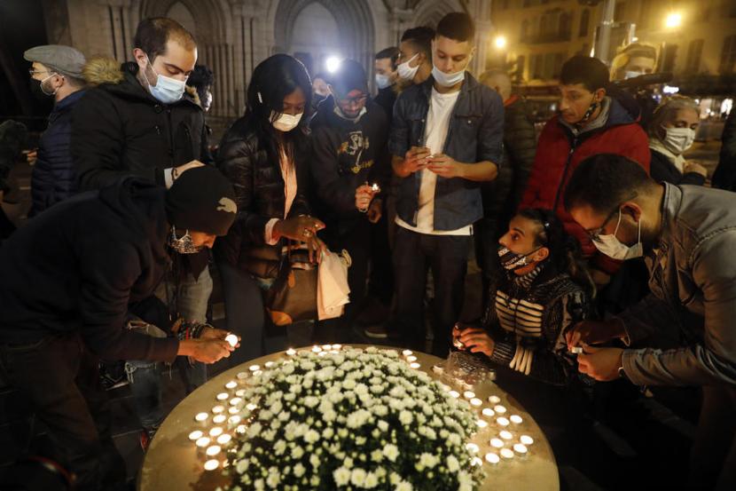 Masyarakat menyalakan lilin tanda berduka di pintu masuk gereja Basilika Notre Dame, Nice, Prancis, Kamis (29/10), menyusul teror di kota tersebut. Tiga orang meninggal akibat serangan di gereja. Insiden ini terjadi kurang dari sebulan setelah pemenggalan guru sekolah Prancis.  