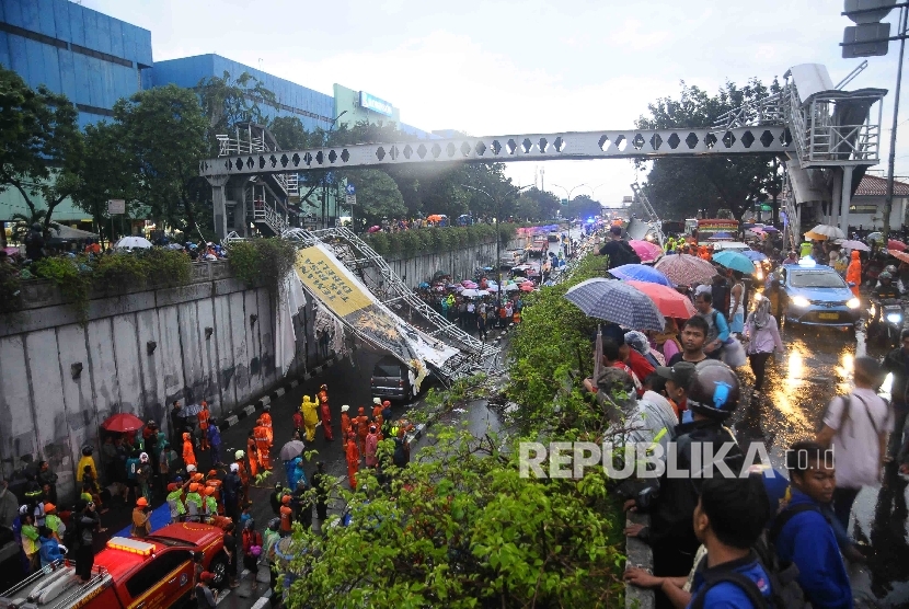 Masyrakat menonton proses evakuasi reruntuhan papan reklame yang roboh dari sebuah JPO di Pasar Minggu, Jakarta Selatan, Sabtu (24/9).