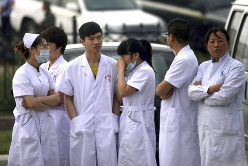 Medical staff wait near a poultry processing plant that was engulfed by a fire in northeast China's Jilin province's Mishazi township on Monday, June 3, 2013. 