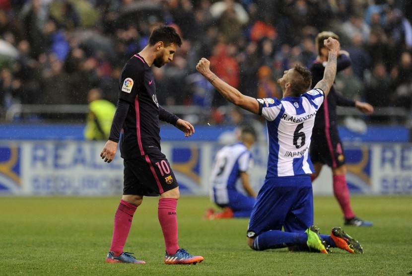 Megabintang Barcelona Lionel Messi (kiri) berjalan melewati pemain Deportivo La Coruna Raul Albentosa seteah kalah 1-2 di Riazor, Ahad (12/3).