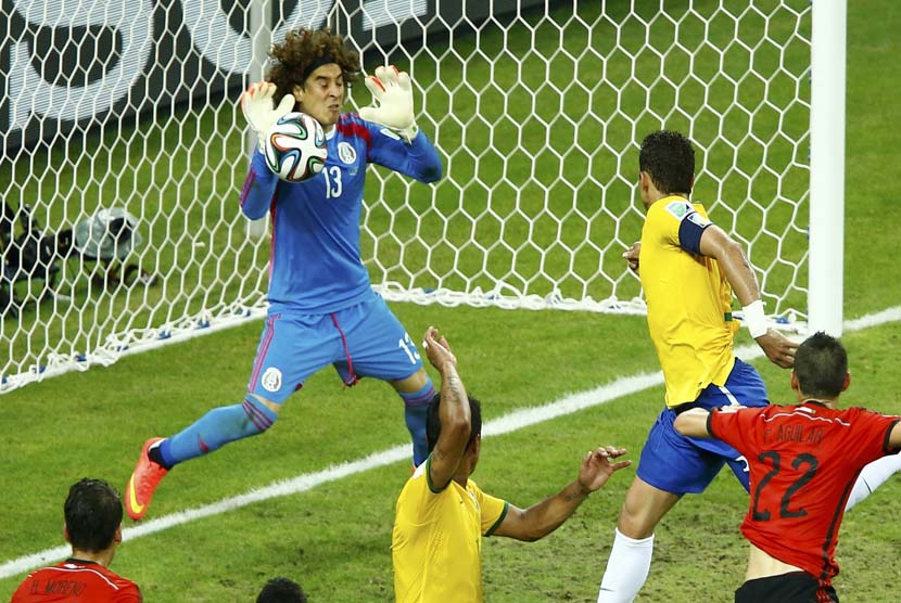 Meksiko Guillermo Ochoa (kiri) mengalihkan bola agar tidak terjadi gol dari Thiago Silva (kanan) dari Brasil dipertandingan sepak bola mereka di arena Castelao di Fortaleza, Selasa (!7/6).   (REUTERS/Mike Blake).