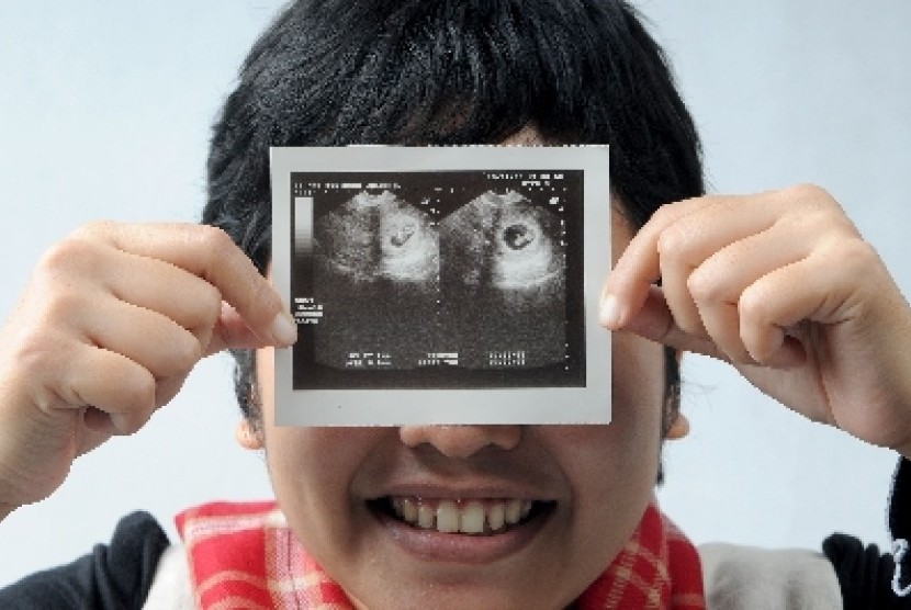 Ibu hamil memperlihatkan USG janinnya. Tim dokter di AS mampu memperbaiki kondisi pembuluh darah yang mematikan pada bayi yang belum lahir.