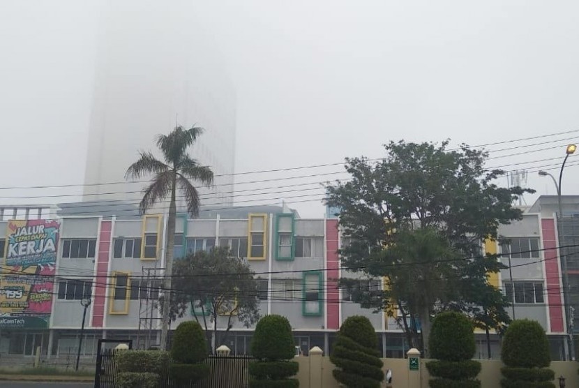 Menara Hotel Wyndham Opi di Kota Palembang, tertutup kabut asap, Jumat (20/9).
