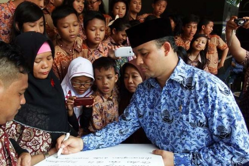  Menbuddikdasmen Anies Baswedan (kanan) disaksikan sejumlah pelajar SD ketika menuliskan kalimat penyemangat untuk para guru usai upacara peringatan Hari Guru Nasional di Kemenbuddikdasmen, Jakarta, Selasa (25/11). 