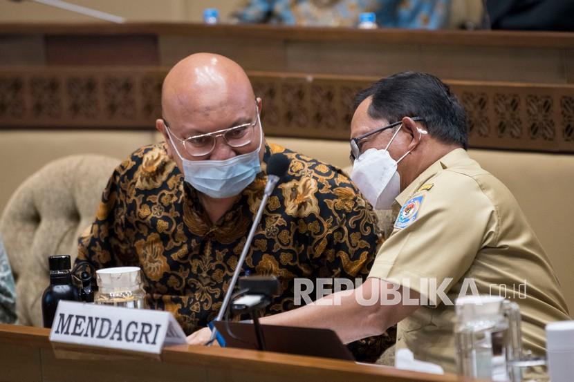 Mendagri Tito Karnavian (kanan) berdiskusi dengan Ketua KPU Ilham Saputra (kiri) sebelum rapat kerja bersama Komisi II DPR dan Bawaslu membahas penyelenggaraan Pemilihan Umum (Pemilu) 2024 di kompleks Parlemen, Jakarta, Senin (24/1/2022). Dalam rapat tersebut disepakati Pemilu 2024 akan digelar pada 14 Februari 2024. 