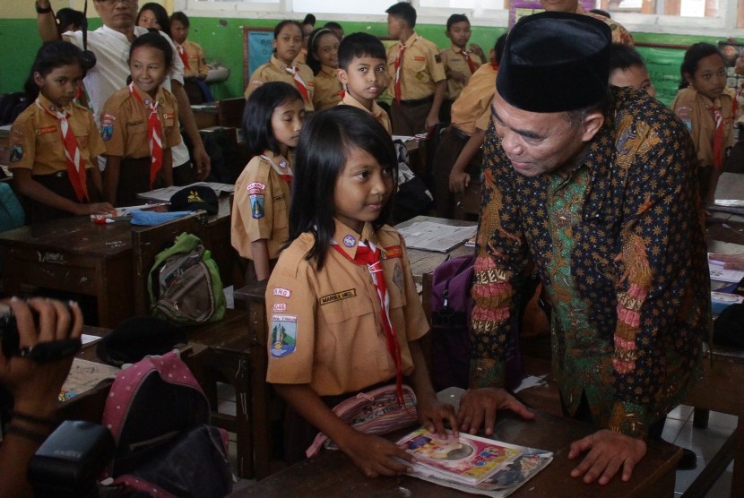 Mendikbud, Muhadjir Effendy (kanan) menanyai seorang siswa saat memantau penyaluran Kartu Indonesia Pintar (KIP) di SDN 1 Mangliawan 1, Malang, Jawa Timur, Jumat (2/9). 