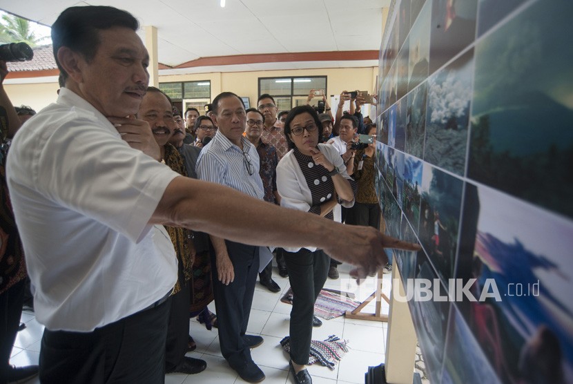 Menko Kemaritiman Luhut Binsar Pandjaitan (kiri) bersama Gubernur Bank Indonesia Agus Martowardojo (kedua kanan) dan Menteri Keuangan Sri Mulyani (kanan) melihat foto-foto erupsi Gunung Agung saat meninjau Pos Pengamatan Gunung Api Agung, di Desa Rendang, Karangasem, Bali, Jumat (22/12).